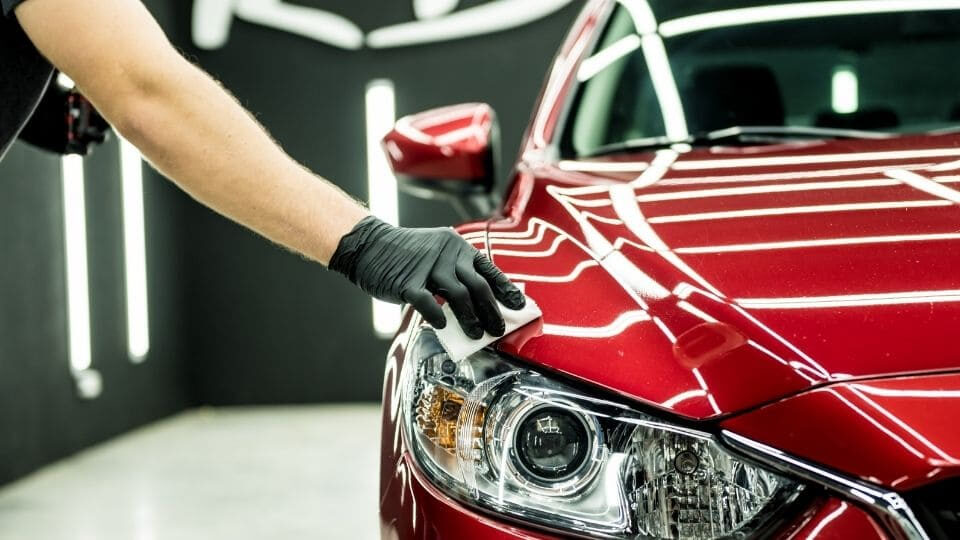 person polishing a red sports car